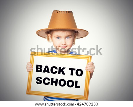 Little Funny girl in striped shirt with blackboard. Text  back to school.  Isolated on gray background