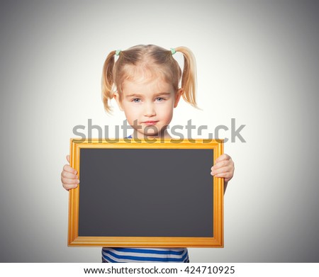 Little Funny girl in striped shirt with blackboard. Isolated on gray background
