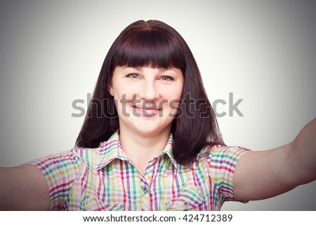Brunette girl makes a selfie on gray background.