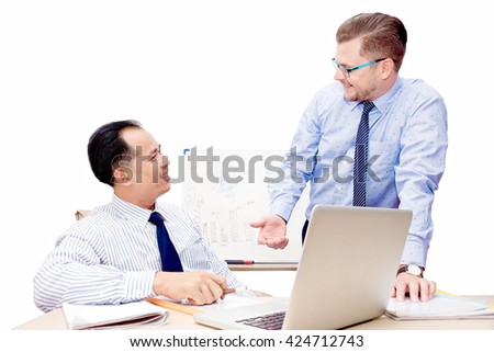 Two handsome young businessmen chatting at desk infront of laptop. Diagrams and graphics in background. Isolated on white. Cooperation, team work concept. Text space