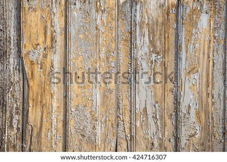 Old damaged vertical board under a layer of old flaky paint with cracks and scratches