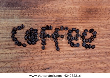 Coffee beans are sorted letters on a wooden background.