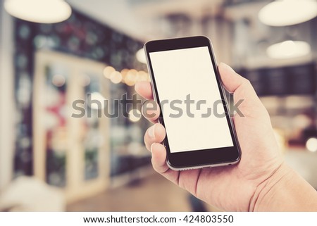 hand holding the phone tablet on blurred in shop or restaurant background;Transactions by smartphone concept