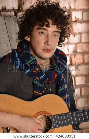 curly man with guitar, strings,dark, brick wall, 