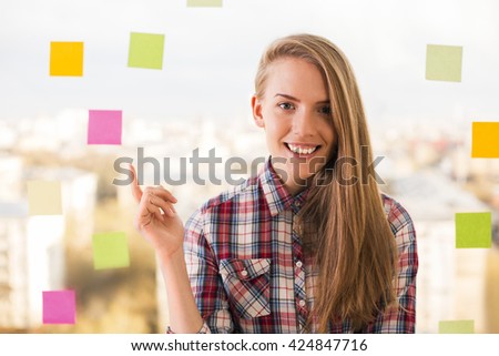 Gorgeous smiling woman standing next to colorful stickers on window with her finger up