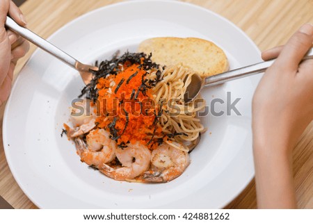 Selective focus of spoon and fork picking shrimp and red caviar spaghetti.