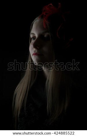 A low key portrait of a teenage girl in a serious mood. With only one light source, red lips, and lovely shadows, this is a dramatic photo for many ideas and concepts. Vertical with copy space.