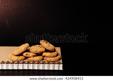 chocolate ship cookies and book in black background