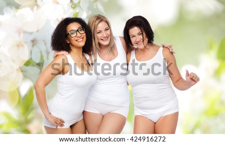 friendship, beauty, body positive and people concept - group of happy plus size women in white underwear over natural spring cherry blossom background