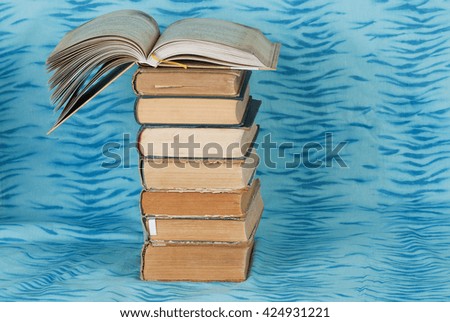 Open book, stack of hardback books  on blue cloth. Back to school. Copy space