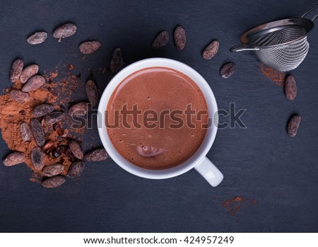 Cocoa in a cup and cocoa beans on the black background, top view