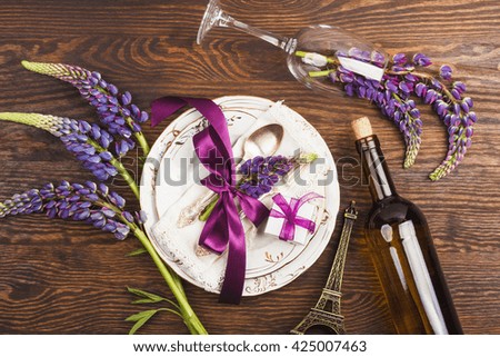 Tableware with violet lupines, silverware and decorations on the wooden background