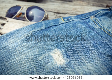 Blue jeans on a wooden background.Frayed jeans on a rough wood surface.