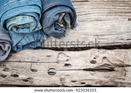Rolls of different worn blue jeans on a wooden background. jeans on a rough wood surface.