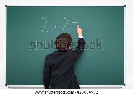 school boy decides examples math on chalkboard background, education exam concept