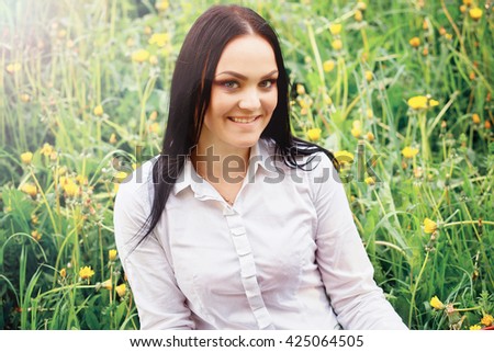 photo of beautiful young woman sitting on a grass
