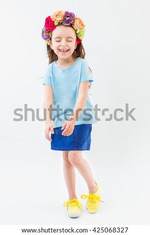 Adorable Laughing delight small girl in blue and yellow clothes. Flowers hair accessory. ashamed embarrassed confused pose. You can place design advertising logo text empty space. Template branding. 