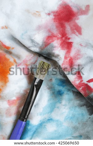 Paint brush on stained colorful cloth as a background