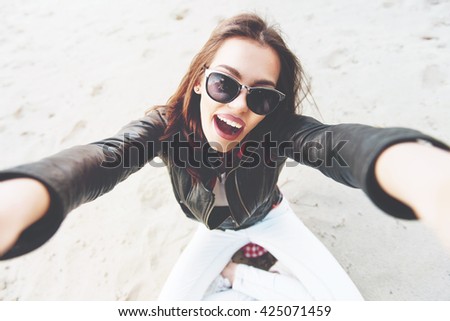 Beautiful, young woman taking a selfie outdoors on the sand