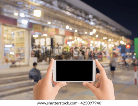 woman use mobile phone and blurred image of street market at night