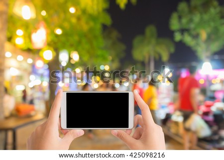 woman use mobile phone and blurred image of street market at night