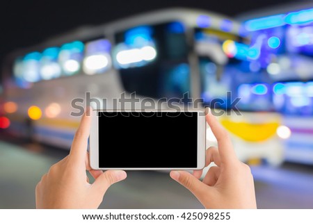 woman use mobile phone and blurred image of bus with beautiful light at night