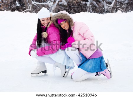 two beautiful girls wearing warm winter clothes ice skating