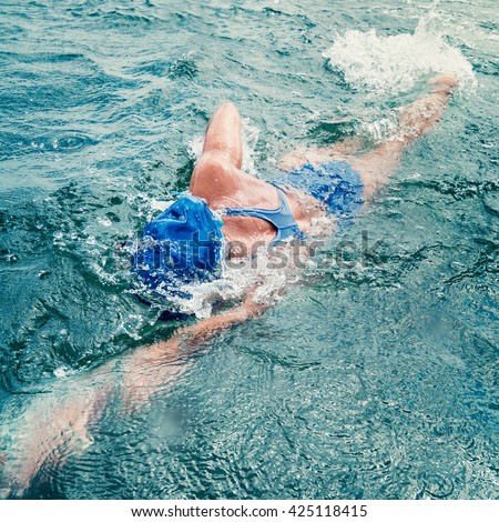 Marathon swimming - female marathon swimming athlete in action. Wide angle photo taken from boat