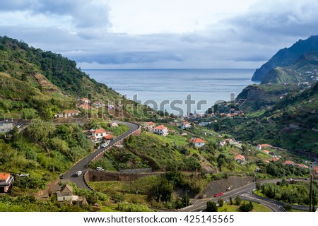 Typical landscape of Madeira island, serpentine mountain road, houses on the hills and ocean view. Aerial view to Porto da Cruz, Madeira, Portugal.