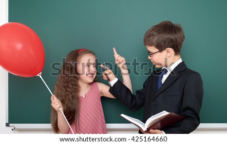 school boy and girl child with balloon on chalkboard background having fun