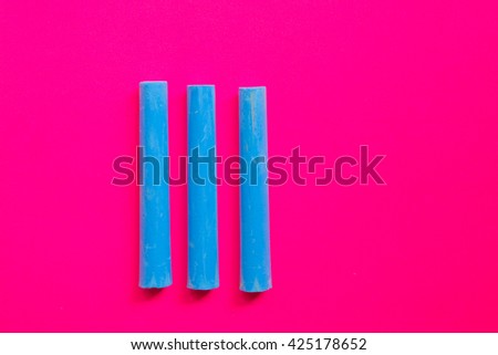 Three blue chalks on pink background