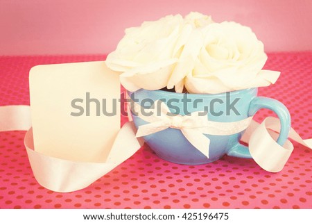 Beautiful fresh roses in a cup. Paper forms and ribbon