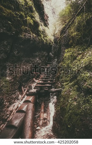 old wooden stairs under the mountain waterfall in deep forest. vintage picture