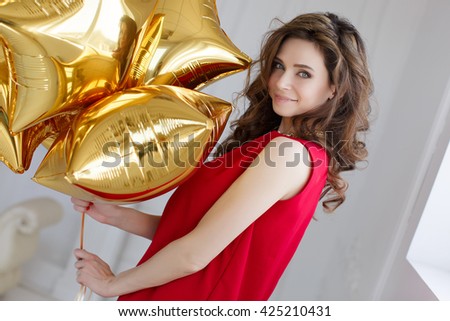 Beautiful woman with balloons. Fashion photo of beautiful woman with balloons. Studio photo. Portrait of a surprised happy woman in red dress holding balloons 