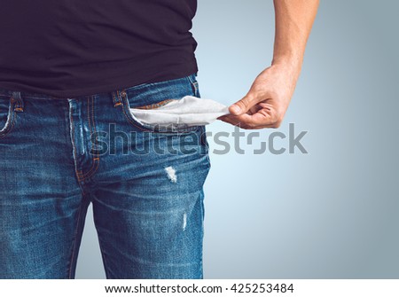 Poor man in jeans with empty pocket Royalty-Free Stock Photo #425253484