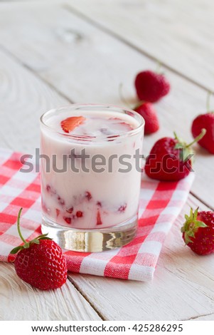 tasty, healthy strawberry yogurt with strawberry pieces on a wooden table