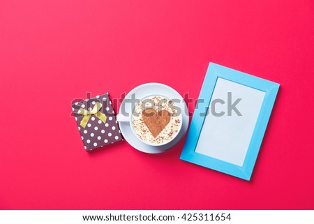 cup of coffee, gift and fphoto frame on the red background