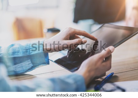 Work Process in Modern Office. Young Account Manager Working at Wood Table with New Business Project.Touching Screen Digital Tablet. Horizontal. Film effect. Blurred background. Flares 