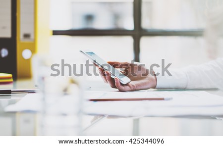 Photo business woman wearing white shirt, holding smartphone hands. Modern loft office. Blurred background. Horizontal picture. Film effect.