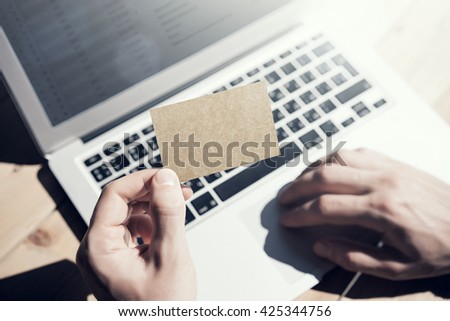 Photo Man Showing Blank Craft Business Card and Using Hand Modern Laptop Blurred Background. Mockup Ready for Private Information. Sunlight Reflections Screen Gadget. Horizontal mock up
