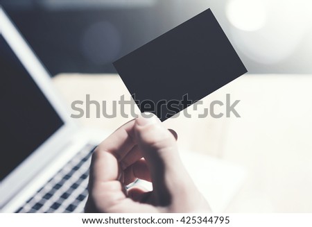 Closeup Photo Man Showing Blank Black Business Card and Using  Modern Laptop on Wood table Blurred Background. Mockup Ready for Private Information. Sunlight Reflections Gadget. Horizontal mock up