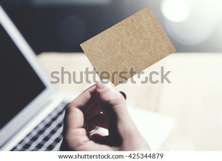 Closeup Photo Man Showing Blank Craft Business Card and Using  Modern Laptop.Wood table Blurred Background. Mockup Ready for Private Information.Sunlight Reflections Screen Gadget.Horizontal mock up