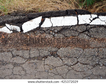 Close-surface asphalt and white lines damaged due to water erosion, cracking and the weight of the truck.