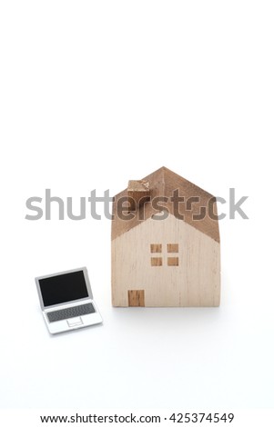Laptop and house.
Miniature house and notebook computer  on white background.