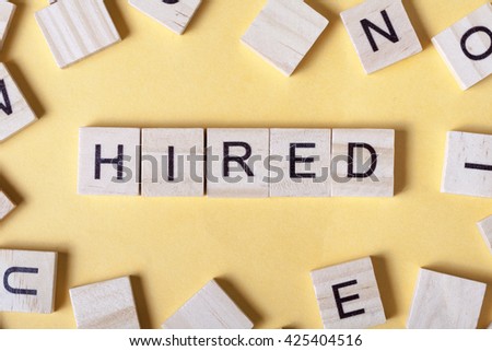 text of HIRED on cubes. Wooden abc.