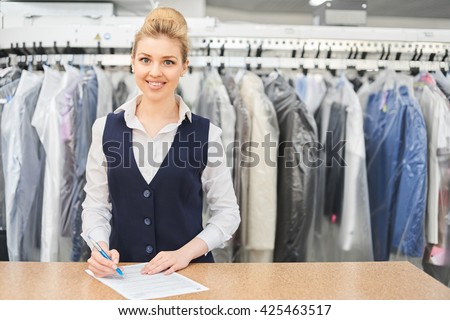 Portrait of a Laundry worker on the background of the clothing on hangers in dry cleaning Royalty-Free Stock Photo #425463517