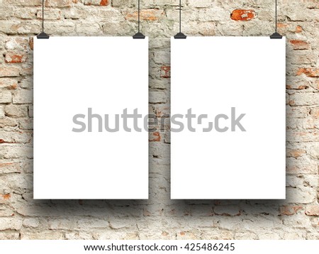 Close-up of two blank frames hanged by clips against old damaged brick wall background