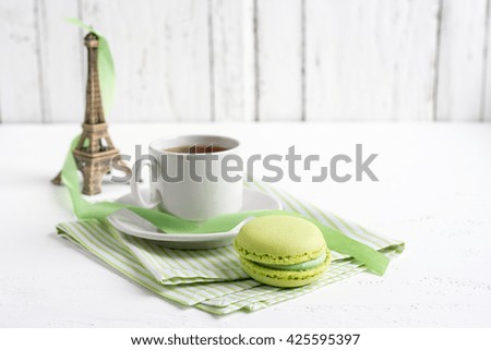 Cup of tea and green French macaroons on a white wooden background. Selective focus.