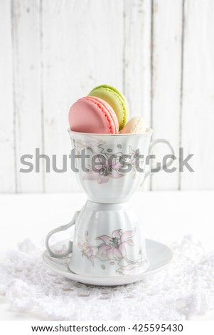 French macaroons in Cup on white wooden background. Selective focus.