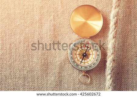 top view of compass and a traveler rope on burlap canvas fabric background. explorer and adventure concept. vintage filtered

